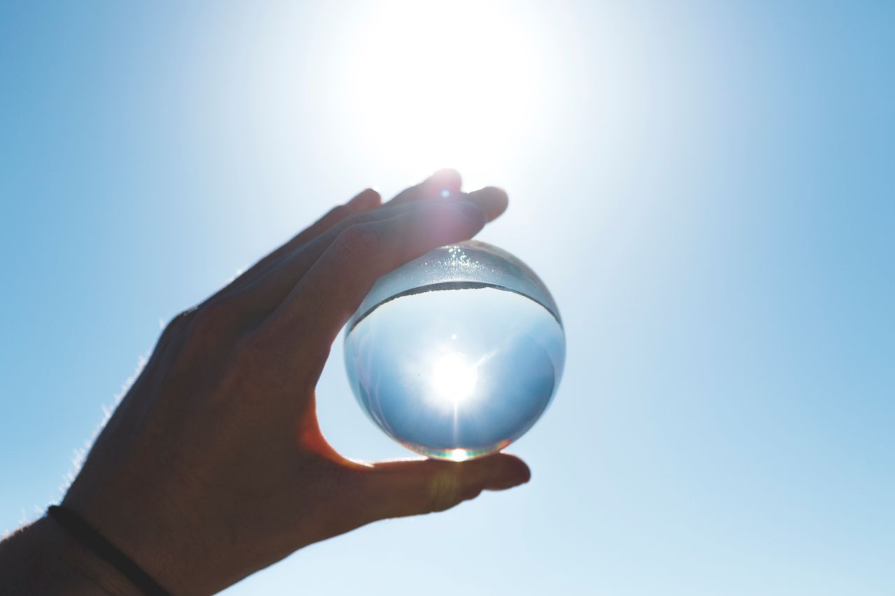 Crafting Captivating Headlines: Your awesome post title goes here A crystal ball held by a hand reflects the bright sun in a clear blue sky.
